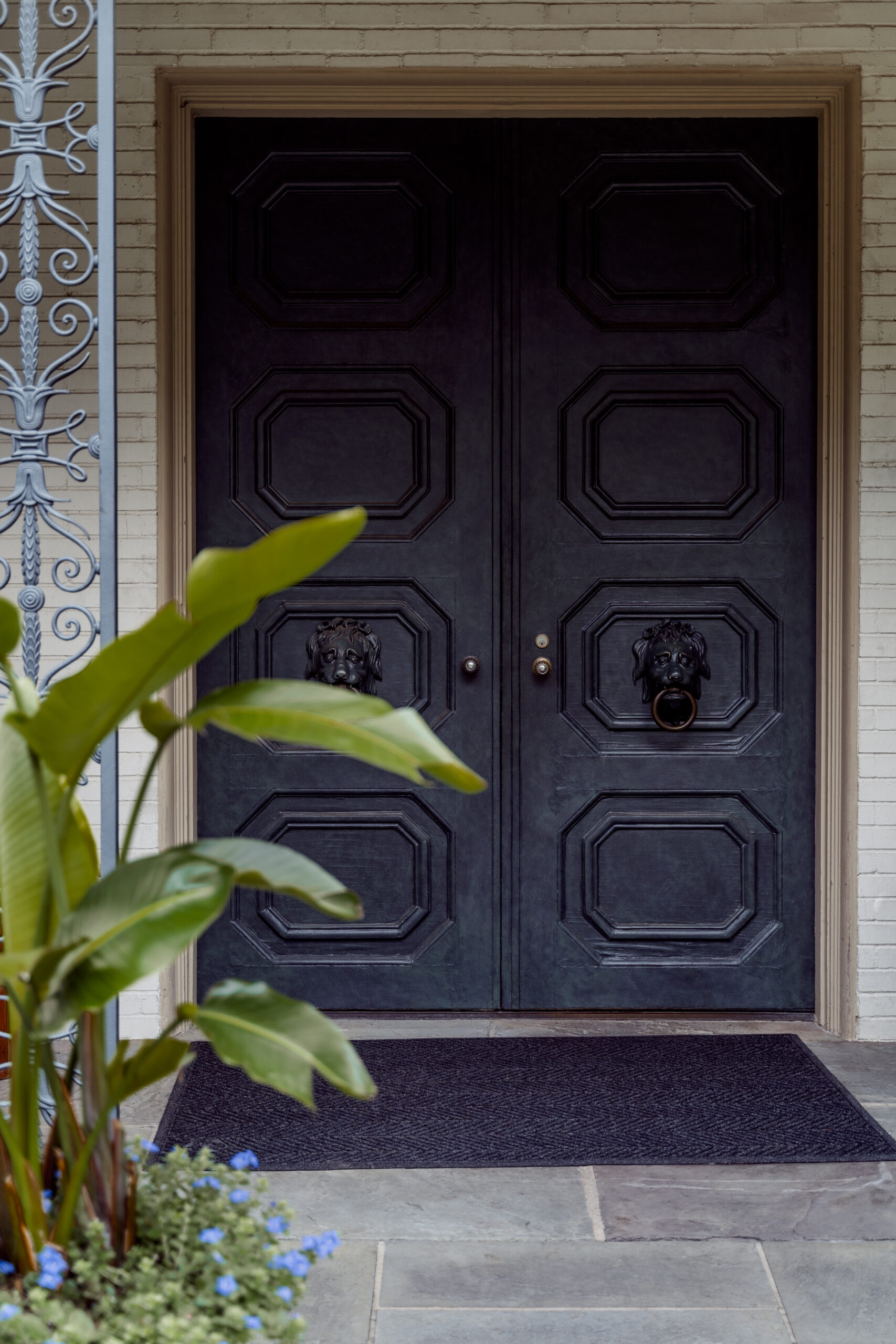 Ornate wooden doors surrounded by greenery at the entrance to Alex Camp House.