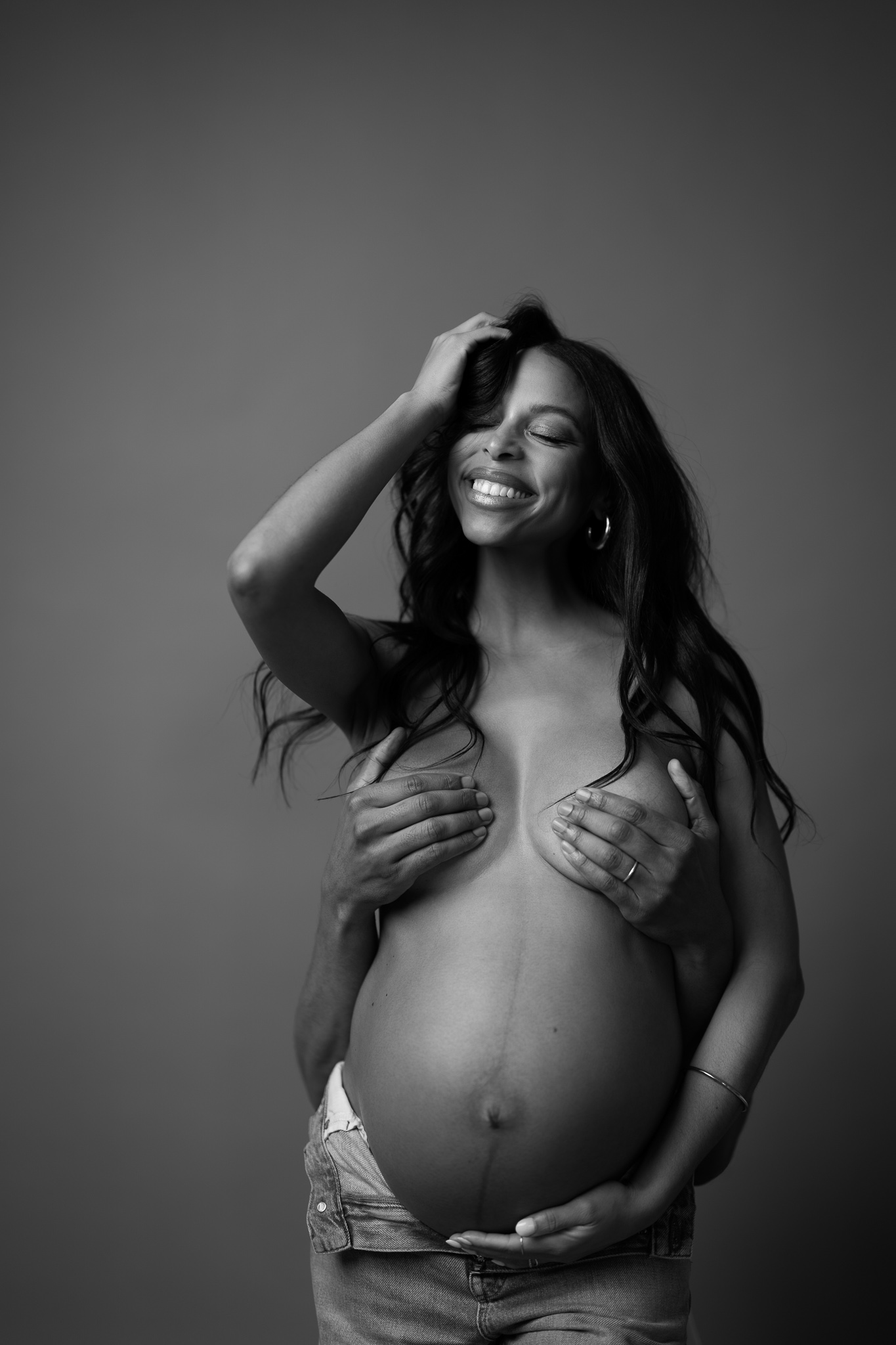A confident pregnant woman smiling joyfully in a bold maternity portrait, inspired by high-fashion editorial photography and the iconic Janet Jackson Rolling Stone cover.