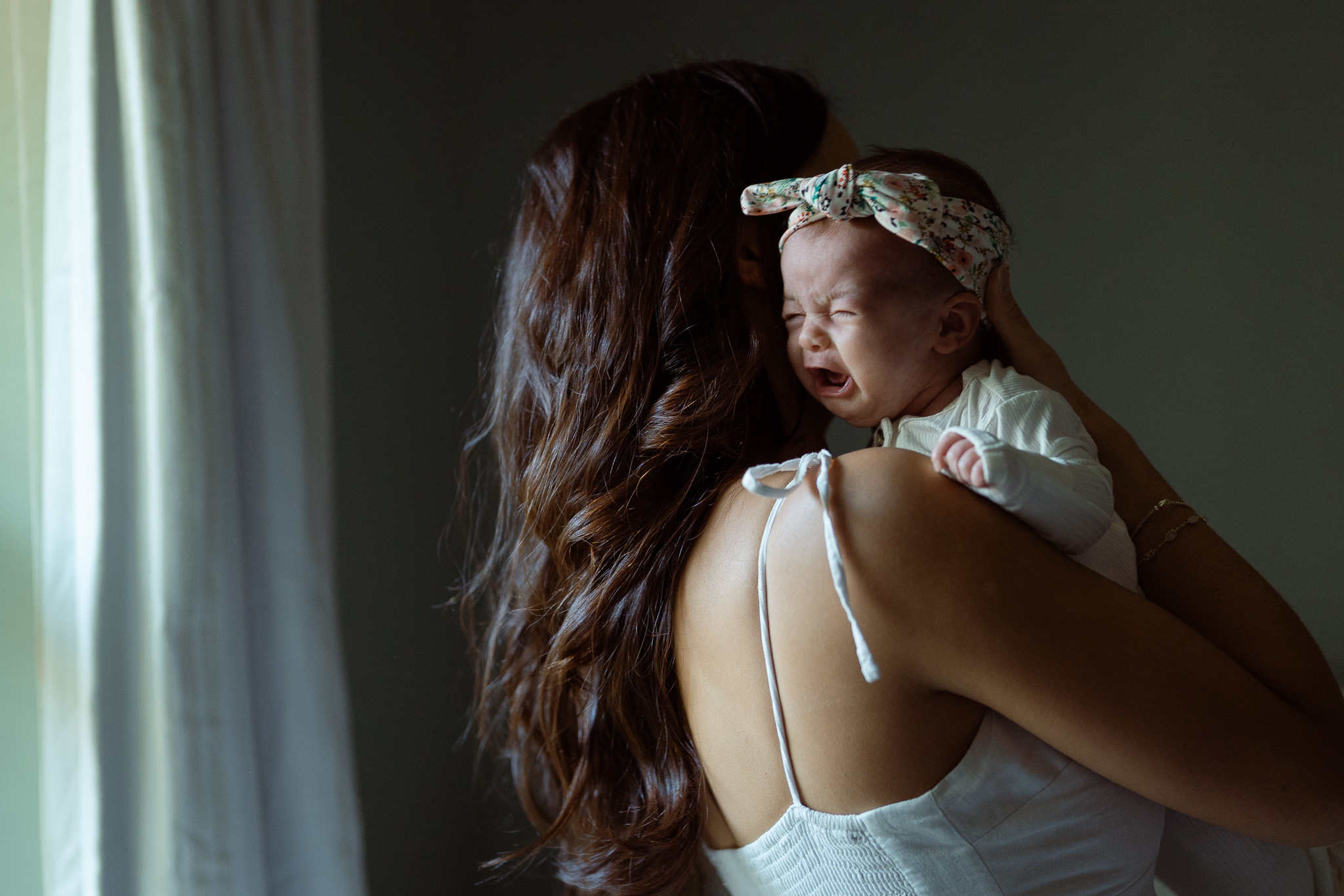 Mother holding her baby close, surrounded by soft natural tones.