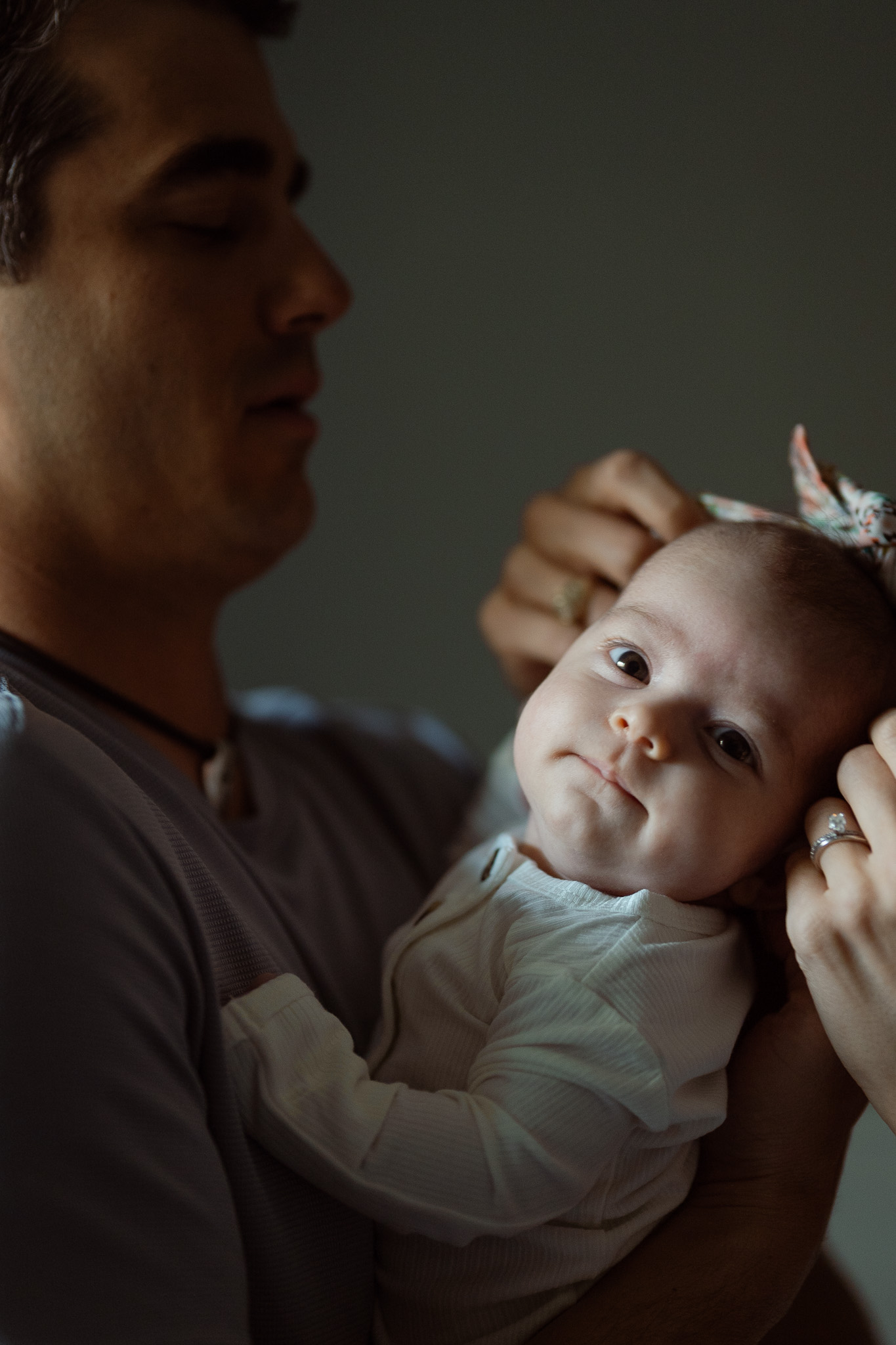 Parents holding their newborn in natural window light during lifestyle newborn photography at home.